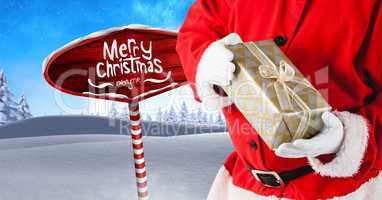 Merry Christmas text and Santa holding gifts with Wooden signpost in Christmas Winter landscape