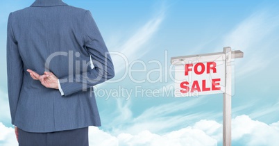 Businesswoman with fingers crossed  and For Sale sign