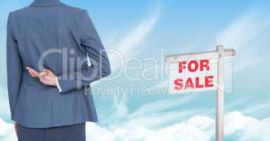 Businesswoman with fingers crossed  and For Sale sign