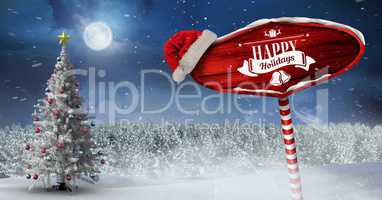 Happy holidays on Wooden signpost in Christmas Winter landscape and Santa hat with Christmas tree
