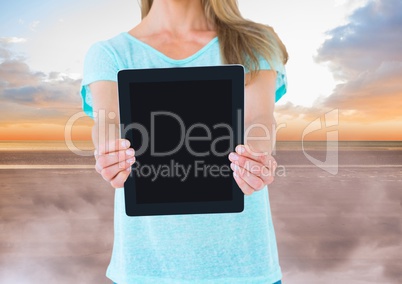 Woman holding tablet with evening sky background