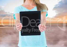 Woman holding tablet with evening sky background