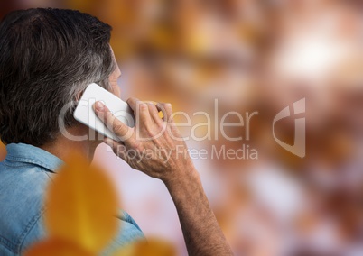 Man on phone in forest with leaves