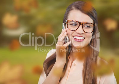 Woman on phone in forest with leaves and glasses