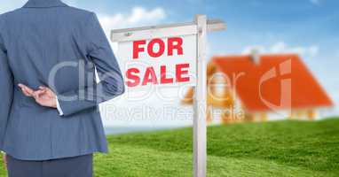 Businesswoman with fingers crossed and For Sale sign