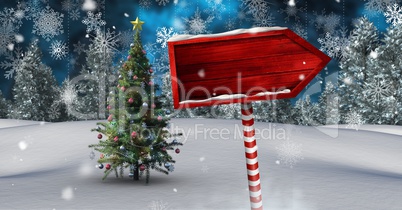 Wooden signpost in Christmas Winter landscape with Christmas tree