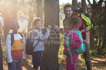 Portrait of teacher and kids examining tree trunk