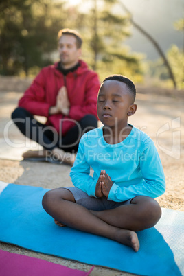 Coach and kid meditating in park