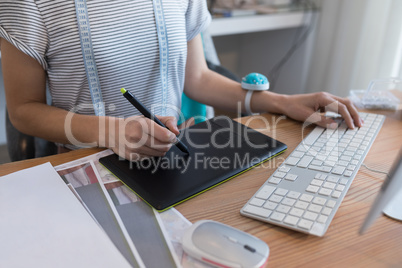 Mid section of female designer using graphic tablet at desk