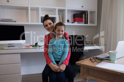 Happy mother and daughter sitting together on chair