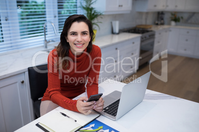 Happy woman using mobile phone at desk