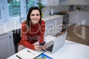 Happy woman using mobile phone at desk