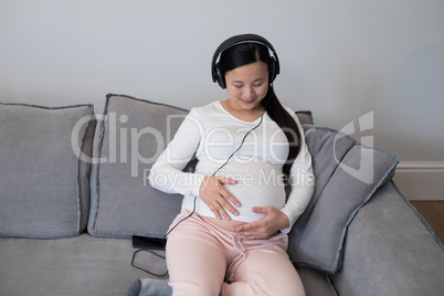 Pregnant woman listening music on headphones