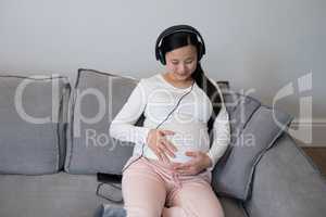 Pregnant woman listening music on headphones