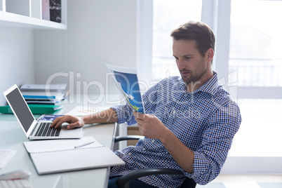 Man looking at graph while using laptop