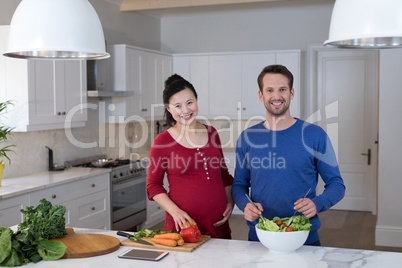 Pregnant couple preparing salad in the kitchen