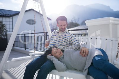 Couple relaxing together on a porch swing in balcony