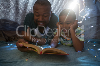 Father and son reading book in bedroom