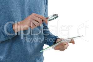 Male executive holding magnifying glass and digital tablet