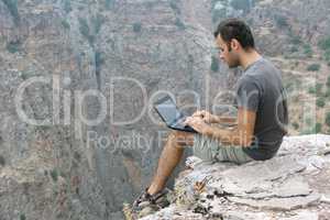 sitting on rock and using laptop, I live on my laptop as I travel, using it to write, work, stay in touch with family and friends