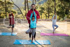 Coach assisting kids in practicing yoga