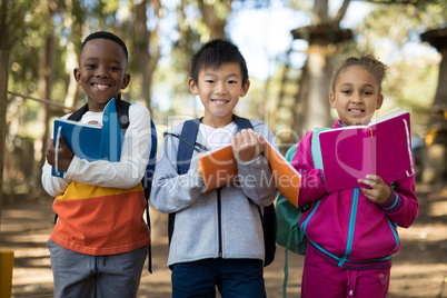 Portrait of kids holding book in park