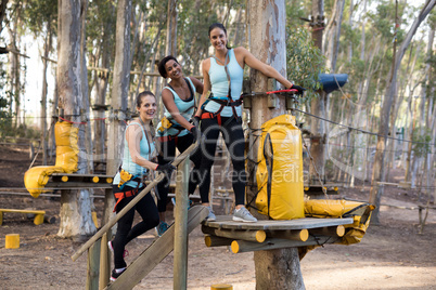 Portrait of happy friends preparing for zip line in forest