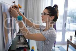 Female designer attaching paper on board