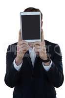 Businessman hiding his face with digital tablet