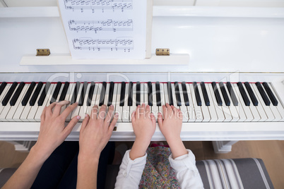 Mid section of mother and daughter playing piano