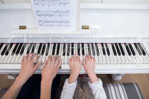 Mid section of mother and daughter playing piano