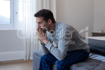 Thoughtful man sitting on bed