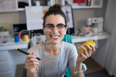 Portrait of smiling female designer holding spool and stylus
