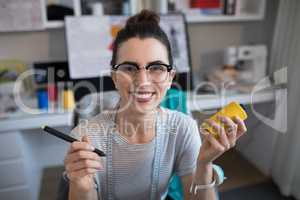 Portrait of smiling female designer holding spool and stylus