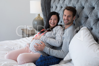 Man and pregnant woman sitting on bed