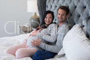 Man and pregnant woman sitting on bed