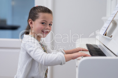 Portrait of cute girl playing piano