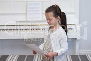 Cute girl looking at musical sheet