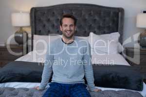 Portrait of happy man sitting on bed