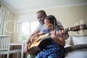 Father teaching his daughter to play the guitar