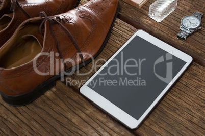Shoes, digital tablet and wristwatch on wooden plank