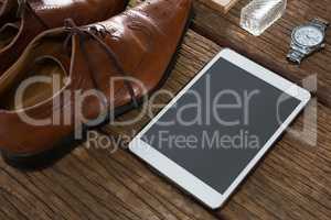 Shoes, digital tablet and wristwatch on wooden plank