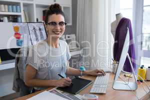 Portrait of female designer using graphic tablet while working on computer