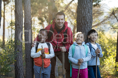 Happy kids and teacher standing in forest