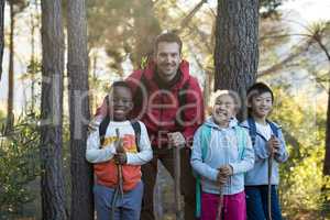 Happy kids and teacher standing in forest