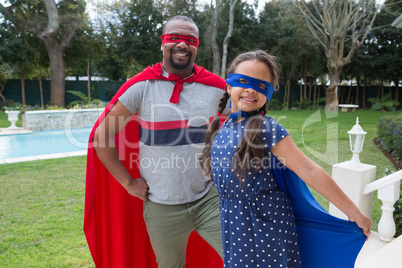 Father and daughter in superhero costume standing in garden