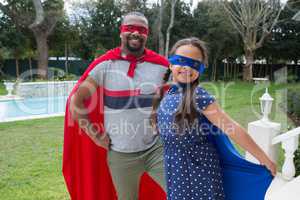 Father and daughter in superhero costume standing in garden