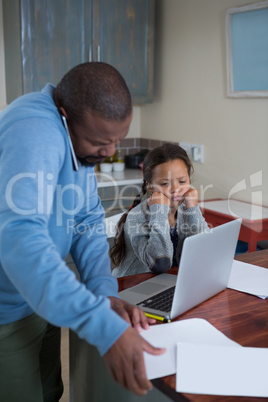 Father talking on mobile phone and daughter watching