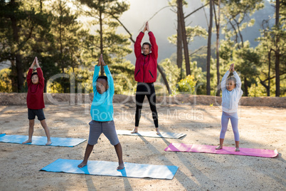 Coach assisting kids in practicing yoga