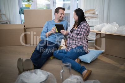 Couple using digital tablet at their new home